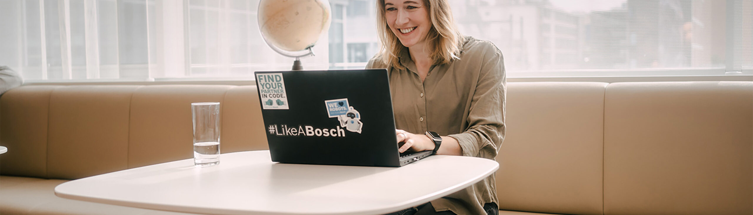 Frau arbeitet an einem Computer auf dem Bosch Sticker kleben