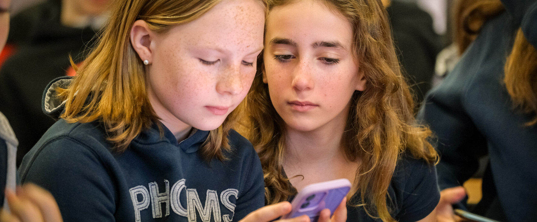 Zwei Schülerinnen schauen auf dem WAKE UP Cybermobbing Projekttag gemeinsam in ein Handy.